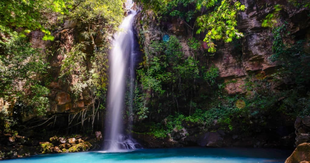 vibrant blue waterfall in costa rica - sustainable tourism with Discova