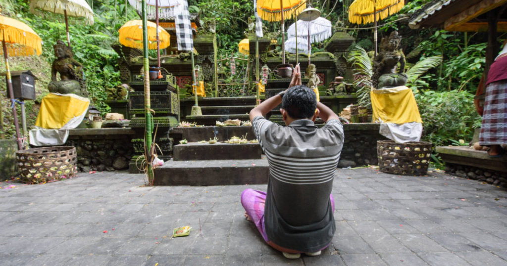 Man practicing Hindu rituals in a temple in Bali, Indonesia