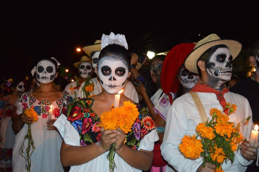 People with skull face paint holding marigolds